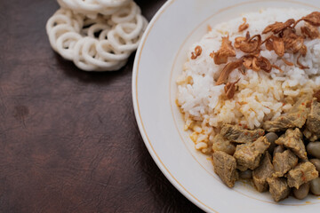 Gulai Kambing or Lamb Curry with rice on a white palte and krupuk, Traditional Javanese mutton curry soup.