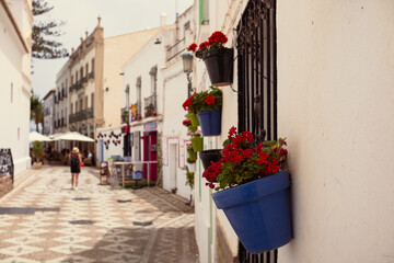 Fototapeta premium Flowers in patterned ceramic vases fixed to the wall of an old house. Decor of the old town of Nerja in Spain