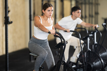 Young woman in sportswear training on exercise bike in gym