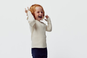 Redhaired little girl expressing joy and playfulness in front of a clean white background