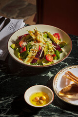 Vegetarian food and white wine. Luxurious and expensive, gourmet food on a black marble table. Avocado, tomatoes, arugula, parmesan and various vegan ingredients