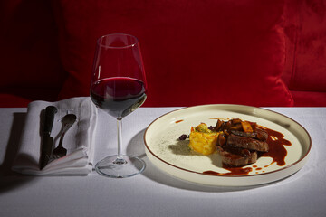 Steak, mashed potatoes as a side dish, a glass of red wine on the side. Elegant dining, a beautifully prepared main course plate and a dinner table.