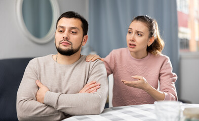 Obraz premium Stressed young adult man feeling irritated after argue with woman asking forgiveness and ignoring her