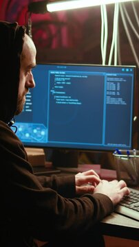 Vertical video Hacker in underground bunker takes advantage of security breach after gaining unauthorized access to system. Rogue programmer hacking network to steal government data, zoom in close up