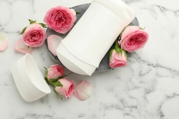 Solid deodorant and beautiful rose flowers on white marble table, top view