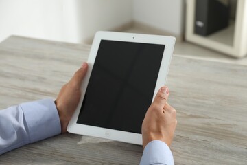 Businessman using tablet at wooden table, closeup. Modern technology