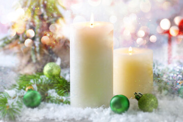 Christmas composition with burning candles on snow, bokeh effect. Festive card