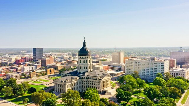 Aerial establishing shot of the Kansas Statehouse and Topeka skyline with forward motion. Topeka is the capital city of the U.S. state of Kansas and the county seat of Shawnee County