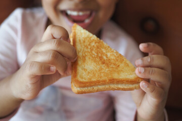 A Joyful Child Happily Holding a TriangleShaped Grilled Cheese Sandwich with excitement