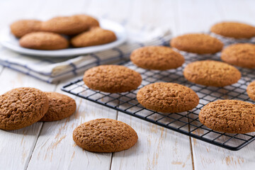 Oatmeal cookies are cooling after baking on a rack on a white table, selective focus.
