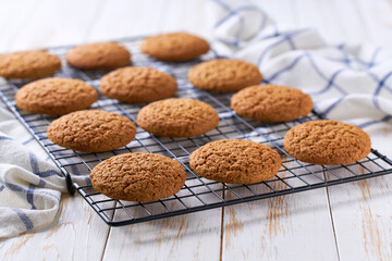 Oatmeal cookies are cooling after baking on a rack on a white table, selective focus.