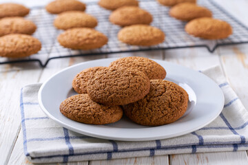 Freshly baked oatmeal cookies cooling on a black wire rack, with in a light kitchen table, selective focus.