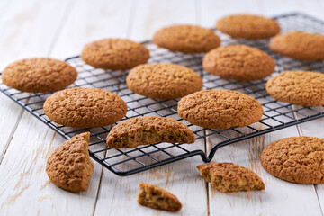 Oatmeal cookies are cooling after baking on a rack on a white table, selective focus.