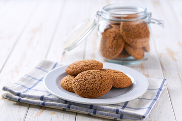 oatmeal cookies in glass jar and on white table, selective focus.