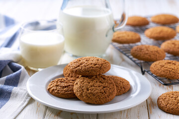 Glass and a jug of fresh milk with oatmeal cookies on a on a white table,selective focus.