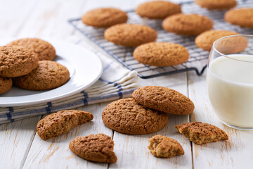 Low-calories oatmeal cookies and glass milk on a white table.