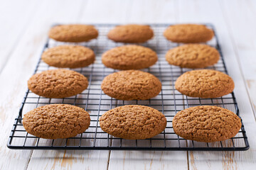 Oatmeal cookies in a black wire rack on a white table, close up.