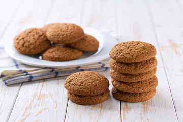 Tasty oatmeal cookies round shape in a plate with on a light kitchen table, selective focus.