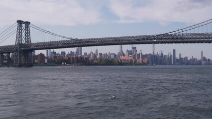 New York City skyline from ferry boat. Manhattan midtown highrise skyscrapers view from ferryboat. East river waterfront panorama, riverfront buildings architecture near water USA. Williamsburg Bridge