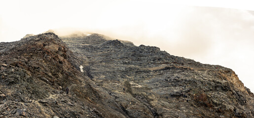 Way over grand couloir on france normal Mont Blanc, rocks and hude rock wall with clouds
