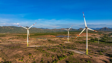 Tall windmill turbines against a clear blue sky, generating renewable energy in the serene Ninh...
