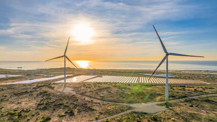 Tall windmill turbines against a clear blue sky, generating renewable energy in the serene Ninh...