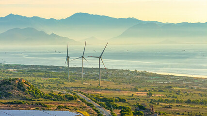 Tall windmill turbines against a clear blue sky, generating renewable energy in the serene Ninh...
