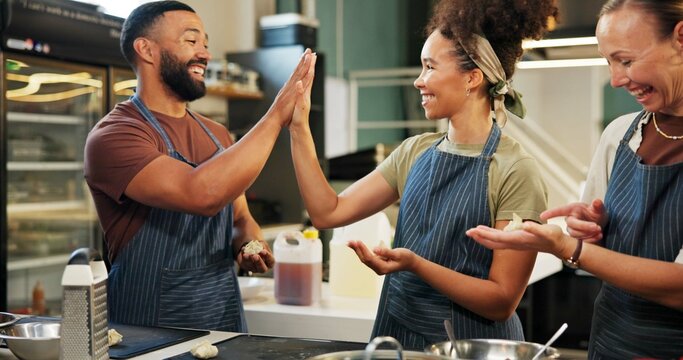 Kitchen, people and chef with smile for high five, celebration and success with achievement for dish. Restaurant, culinary students and cook with hand gesture for support, catering and hospitality