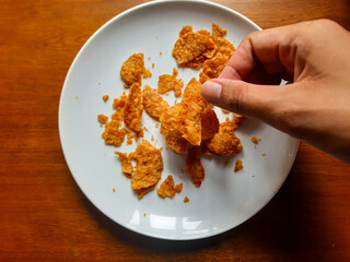 processed from tempeh, namely tempeh chips that are given spicy and salty seasoning on a white plate