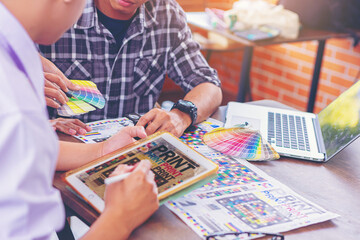 Team graphic designer checking print quality of media graphics proof print and color guides in...