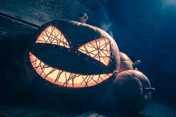 Creepy and scary Jack-o-lantern in wooden shack.