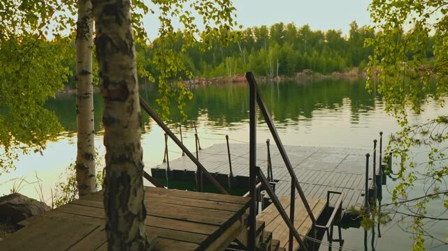 View from the forest to the water launch. View of the panton of the lake. Panton against the backdrop of a lake and forest. Quiet summer evening on the shore of the lake.