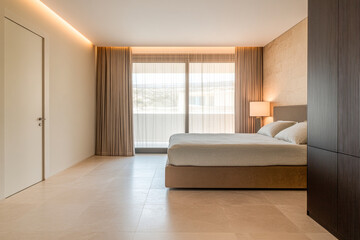 Modern minimalist bedroom featuring a large window and natural light in a contemporary home