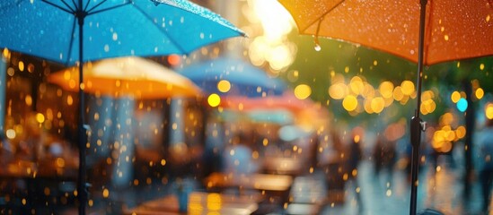 Colorful umbrellas over a blurred street scene of cafe tables with rain falling.