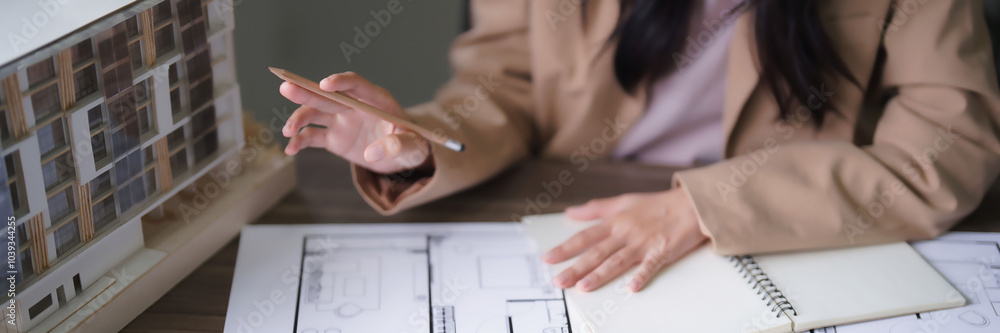 Poster female architect looking on building model and designing architecture interior project on blueprint