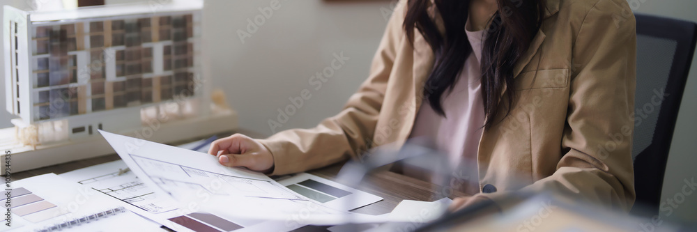Poster female architect checking sketch of interior building project and color swatch sample on blueprint