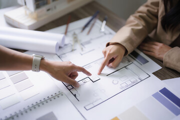 Two female architect discussion and brainstorming to design interior building project on blueprint