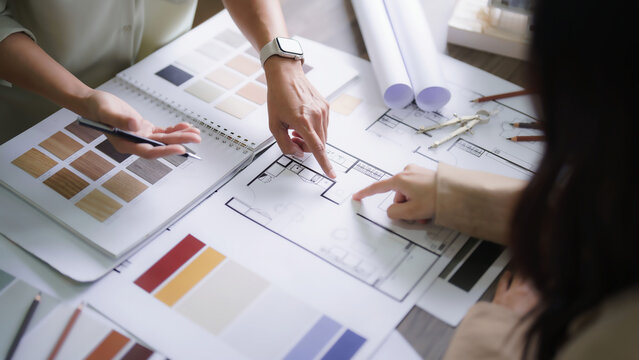 Two female architect discussion and brainstorming to design interior building project on blueprint - Powered by Adobe