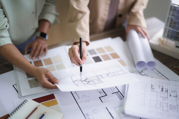 Two female architects discuss and brainstorm about interior designing building project on blueprint