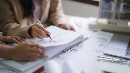 Two female architects discussing about interior designing building project and drawing on blueprint