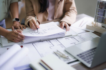 Two female architects discussing about interior designing building project and drawing on blueprint
