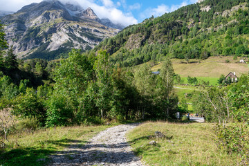 A mountain range with a path leading to a house