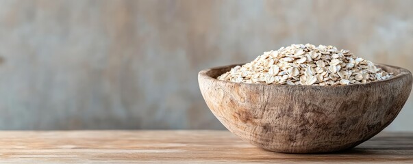 Oats in a rustic wooden bowl on a wooden surface, natural light background.