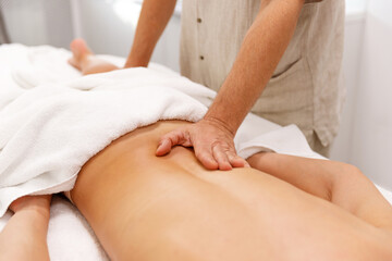 A relaxing back massage performed by a woman's hands, emphasizing comfort and wellness. Ideal for themes of spa treatments, body care, and therapeutic massage