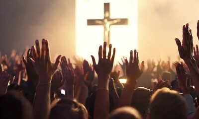 Crowd of people raising hands towards a large illuminated cross in the background.