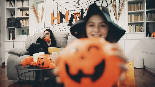 Children are blowing balloon and enjoy funny to prepare Halloween celebrate party  in living rom decorate with pumpkin head and spider web together.
