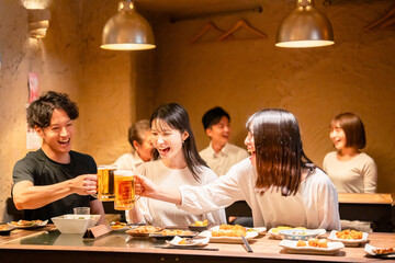 居酒屋でお酒を飲む若い男女
