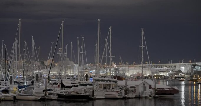 boats in the harbor marina at night covered in snow