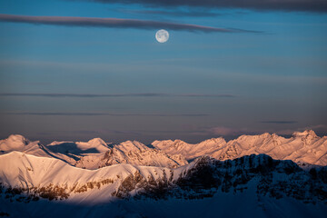 Moon over the queyras mountain range in winter at sunrise