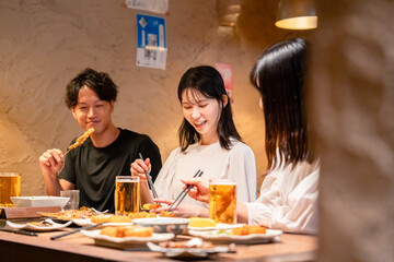 居酒屋でお酒を飲む若い男女